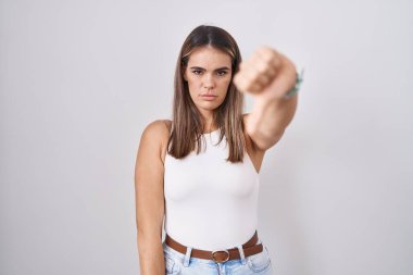 Beyaz arka planda duran Latin kökenli genç bir kadın mutsuz ve kızgın görünüyor. Reddedilmiş ve olumsuz bir hareket sergiliyor. kötü ifade. 