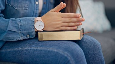 Elleri İncil 'in üzerinde dua eden genç, güzel İspanyol kadın.