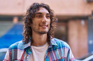Young hispanic man smiling confident looking to the side at street