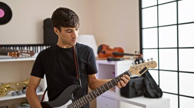 Çekici, genç İspanyol bir adam müzik stüdyosunda elektro gitar çalıyor. Enstrümanına odaklanan yetişkin bir müzisyenin portresi. Büyüleyici bir elektrik sesi yaratıyor.