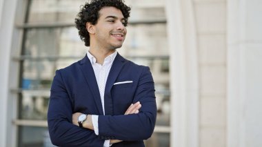 Young latin man business worker smiling confident standing with arms crossed gesture at street