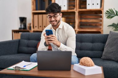 Laptop ve akıllı telefon psikoloji merkezi kullanan genç bir İspanyol psikolog.