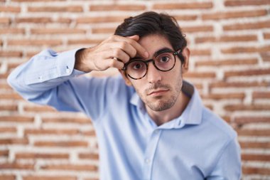 Duvarın arkasında dikilen Latin asıllı genç adam alnındaki sivilceden mutsuz olduğunu gösteriyor. Siyah noktalı çirkin bir enfeksiyon. sivilce ve deri problemi 