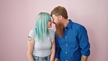 Kadın ve erkek, pembe arka planda birbirlerine güvenerek sırıtıyorlar.