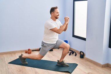 Spor merkezinde kendine güvenen beyaz bir adam gülümsüyor.