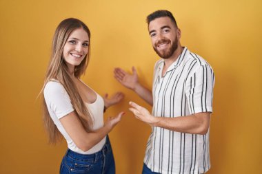 Sarı arka planda duran genç çift gülümseyerek doğal bir şekilde içeri girmeye davet ediyor. 