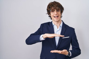 İspanyol iş adamı gözlüklü genç adam. Elleriyle işaret ediyor. Büyük ve büyük boy işareti, ölçü sembolü. Kameraya bakıp gülümsüyor. ölçüm kavramı. 