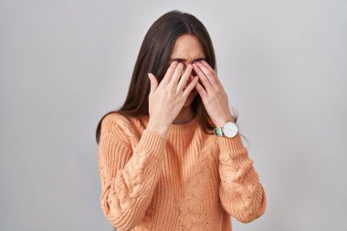 Genç esmer kadın beyaz arka planda duruyor. Yorgunluk ve baş ağrısı için gözlerini ovuşturuyor. Uykulu ve yorgun bir ifade. görme sorunu 