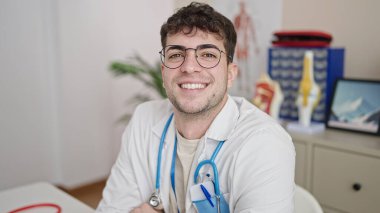 Genç İspanyol doktor klinikte kendinden emin gülümsüyor.