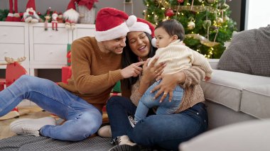Çift ve oğul evdeki Noel ağacının yanında oturmuş birbirlerine sarılıyorlar.
