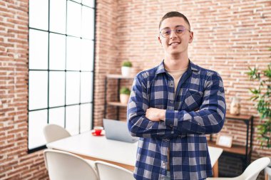 Young hispanic man standing with arms crossed gesture at home