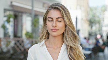 Young blonde woman breathing with closed eyes at street