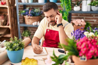 Genç İspanyol çiçekçi çiçekçinin çiçekçide defterine akıllı telefon yazısıyla konuşuyor.