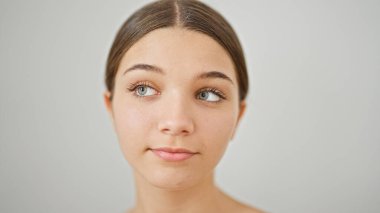 Rahat bir ifadeyle duran genç ve güzel bir kız izole edilmiş beyaz arka plan üzerinden yan tarafa bakıyor.