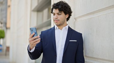 Sokakta akıllı telefon kullanan genç Latin bir iş adamı.