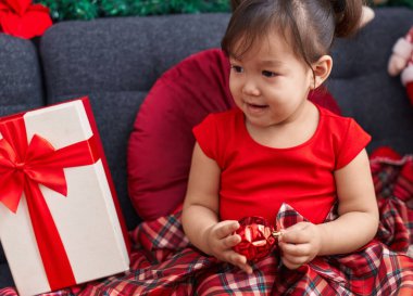 Evdeki Noel süslemeleriyle koltukta oturan sevimli Çinli kız.