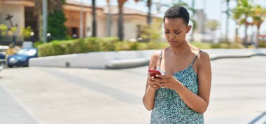 Parkta akıllı telefon kullanan Afro-Amerikalı kadın.