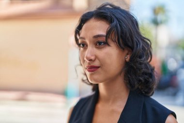 Young beautiful hispanic woman with relaxed expression standing at street