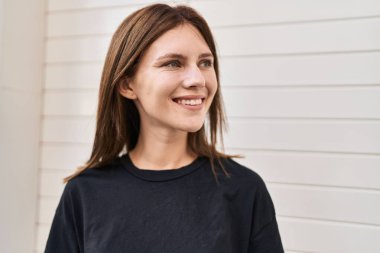 Genç sarışın kadın, kendinden emin bir şekilde beyaz arka plan üzerinden yan tarafa bakıyor.