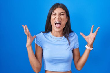 Mavi arka planda duran esmer genç kadın başarının çılgınlığını kollarını kaldırarak ve gözlerini kapatarak sevinçle bağırarak kutluyor. Kazanan konsept 