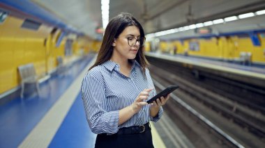 Madrid metro istasyonunda akıllı telefon kullanan güzel İspanyol bir kadın metroda bekliyor.