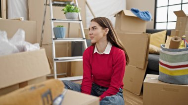 Genç İspanyol kadın gülümsüyor. Kendine güvenen yeni evinde yerde oturuyor.