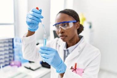Laboratuvarda test tüpüne sıvı döken Afrikalı Amerikalı kadın bilim adamı.