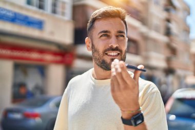 Genç İspanyol adam gülümsüyor. Kendine güveniyor. Sokakta akıllı telefondan konuşuyor.