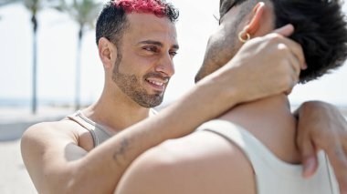 Two men couple smiling confident hugging each other at street