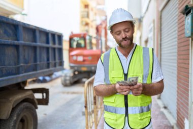 Middle age man architect smiling confident counting dollars at street