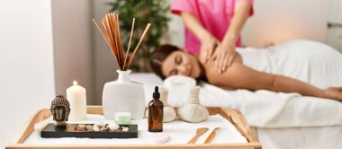 Young beautiful hispanic woman lying on table having back massage at beauty salon