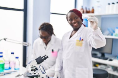 African american women scientists looking sample writing on document at laboratory