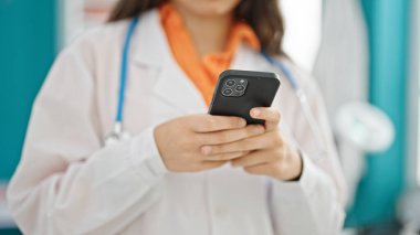 Klinikte akıllı telefon kullanan genç, güzel İspanyol kadın doktor.