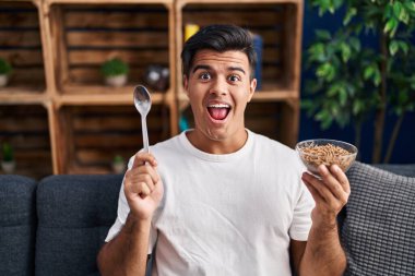 İspanyol adam sağlıklı tahıl gevrekleri yiyor kaşıkla çılgınlığı kutluyor ve başarıya hayret ediyor gözleri açık heyecanla bağırıyor. 