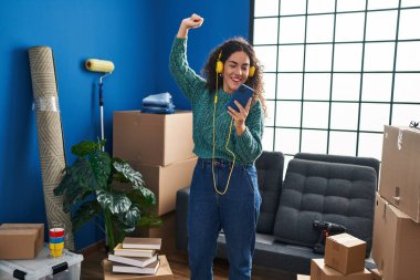 Genç, güzel İspanyol bir kadın yeni evinde müzik dinliyor ve dans ediyor.