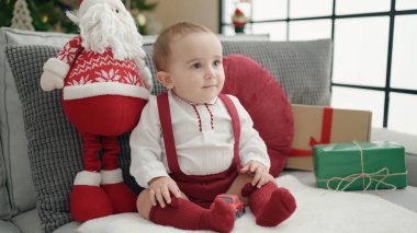 Evdeki Noel ağacının yanında kendine güvenen sevimli İspanyol bebek.