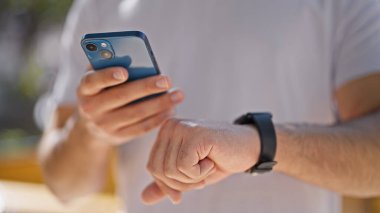 Parkta akıllı telefon ve akıllı telefon kullanan genç bir latin.