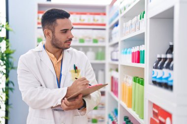 Genç İspanyol eczacı eczanede ciddi bir ifadeyle dokümana yazı yazıyor.