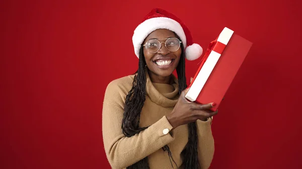 Donna Africana Sorridente Fiducioso Tenendo Regalo Natale Sfondo Rosso Isolato — Foto Stock