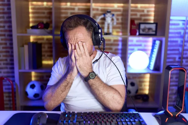 泣きながら手で顔を覆う悲しい表情のヘッドフォンを着てビデオゲームをする中年男性 うつ病コンセプト — ストック写真