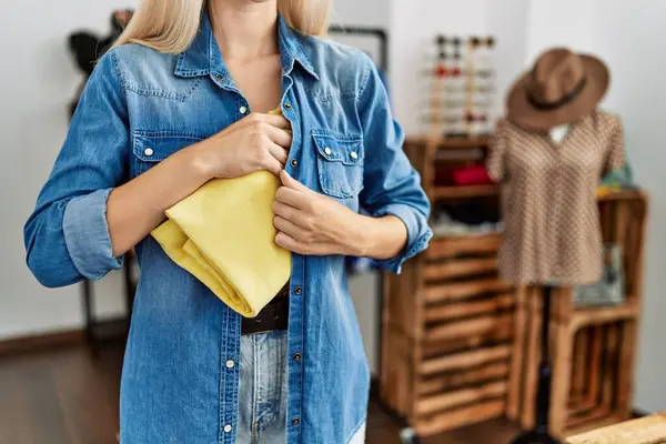 Young blonde woman thief stealing handbag at clothing store