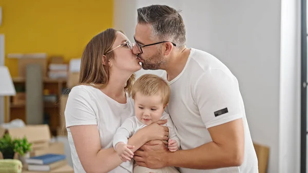 Family of mother, father and baby kissing at new home