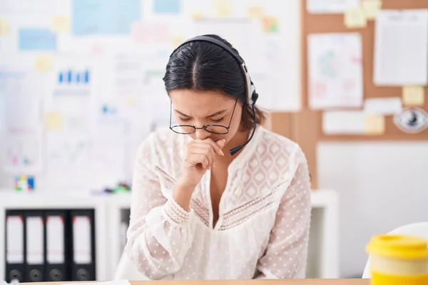 Hispanic young woman working at the office wearing headset and glasses feeling unwell and coughing as symptom for cold or bronchitis. health care concept.