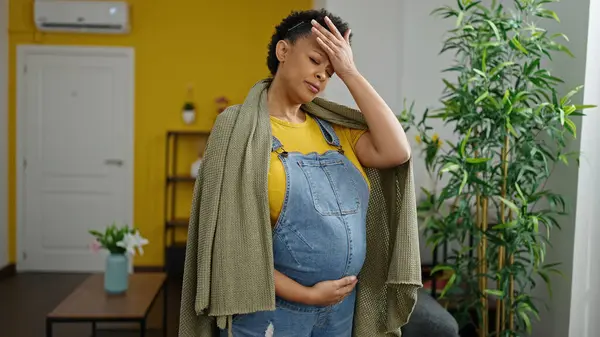 Young pregnant woman coughing touching belly at home