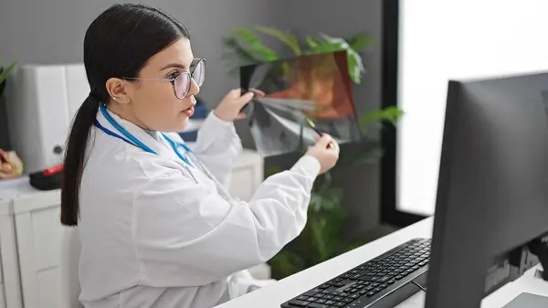 Young hispanic woman doctor on online appointment showing xray at clinic