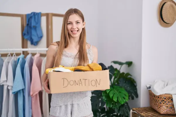 面白い表現で幸せな舌を突き刺す慈善団体のための寄付箱を保持している若い白人女性 — ストック写真
