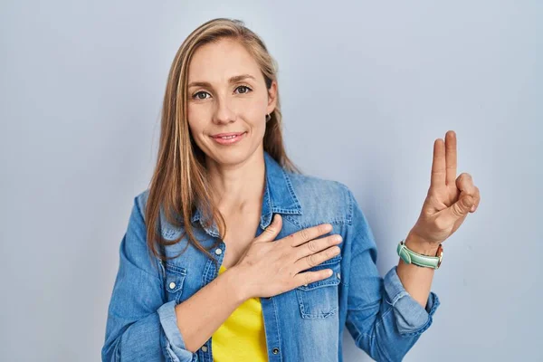 Young Blonde Woman Standing Blue Background Smiling Swearing Hand Chest — Stock Photo, Image
