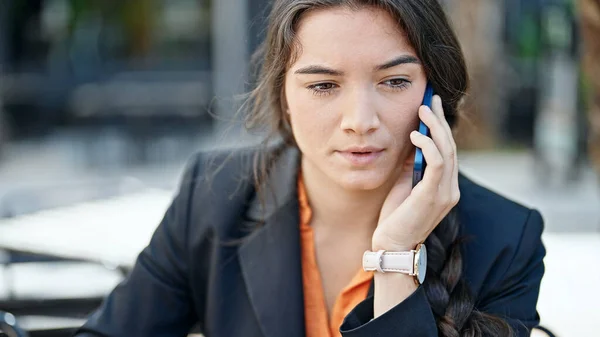 若い美しいヒスパニック系女性のビジネスワーカーがコーヒーショップテラスで勝者の式でスマートフォンで話しています — ストック写真