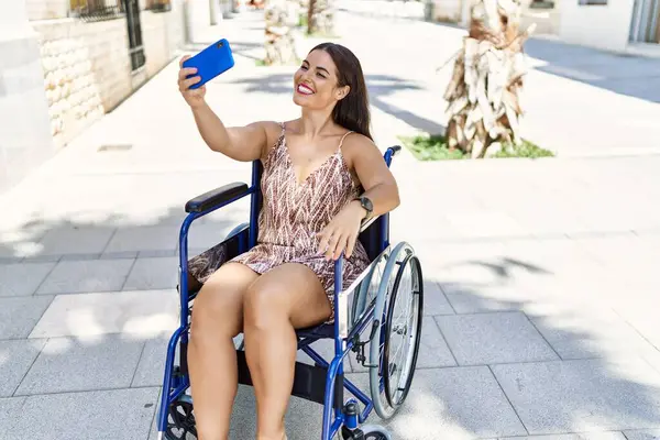 若い美しいですヒスパニック女性作る自殺によってスマートフォン座って車椅子に路上 — ストック写真
