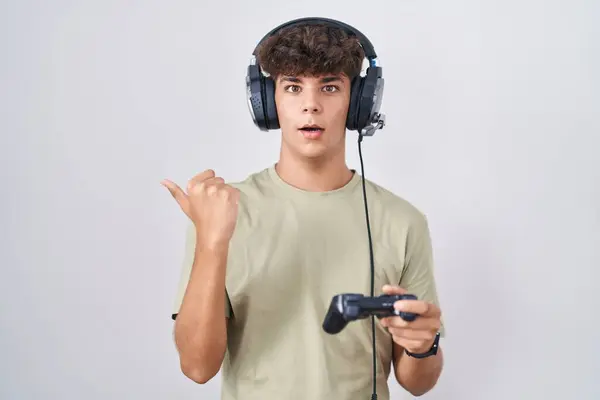 Adolescente Hispano Jugando Videojuego Sosteniendo Controlador Sorprendido Apuntando Con Dedo —  Fotos de Stock